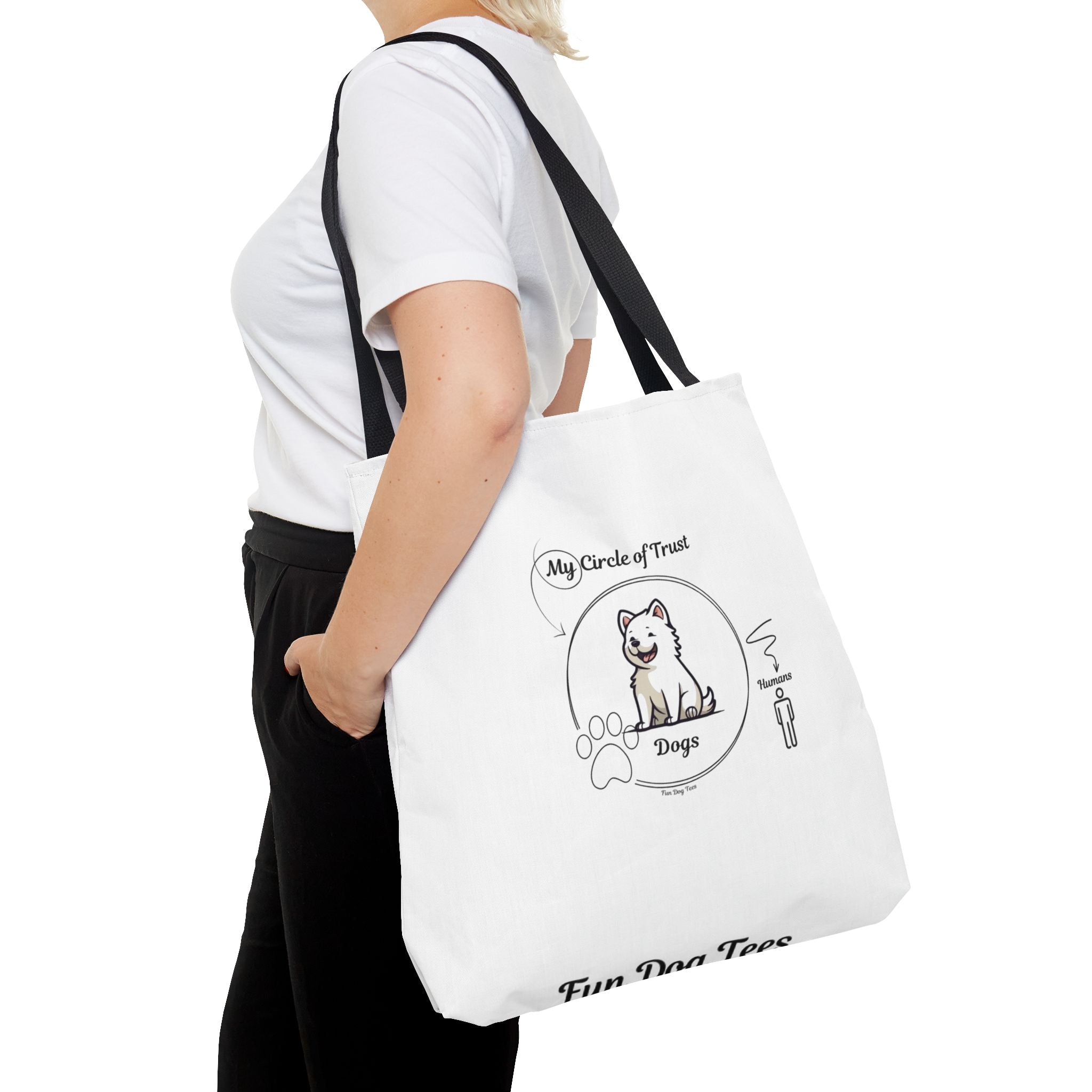 Person holding a white tote bag with a dog illustration and text on a white background